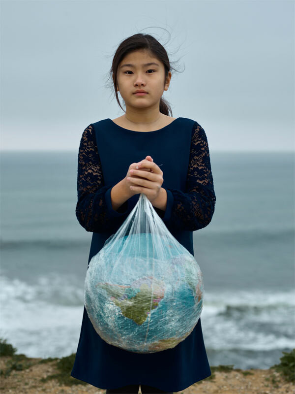 Kind das von Klimawandelbetroffen ist und die Weltkugel in einer Plastiktüte hält